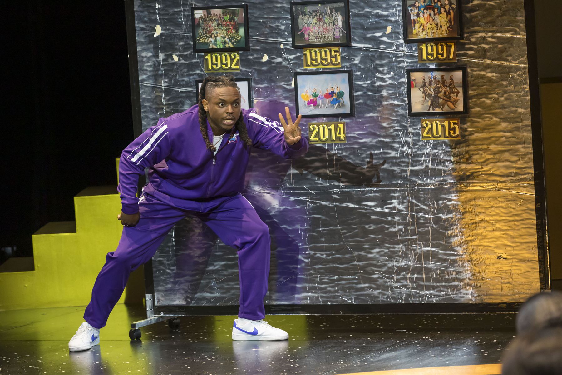 Dance Teacher Pat in a fierce lunge before a wall of trophy photos